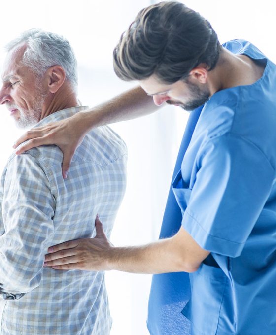 Doctor gently checking an older patient's shoulder